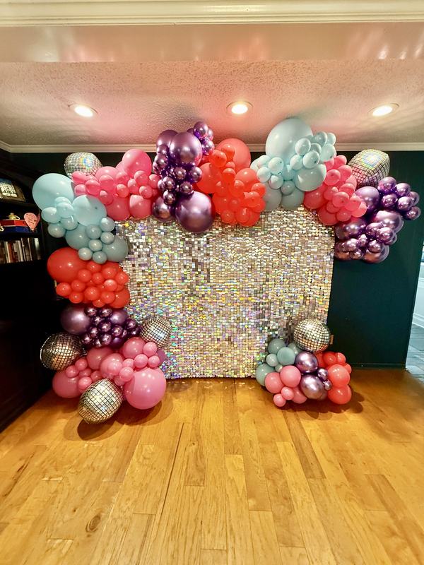 Silver sequin photo wall framed by a full balloon garland